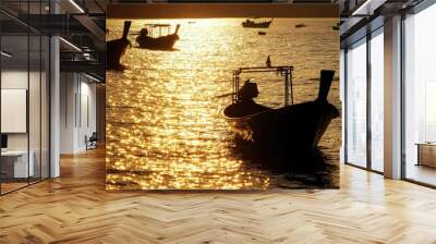 Silhouettes of fishing long-tail boats in the sea at dawn, with the golden reflection of sunlight glistening on the water at Rawai Beach, Phuket. Wall mural