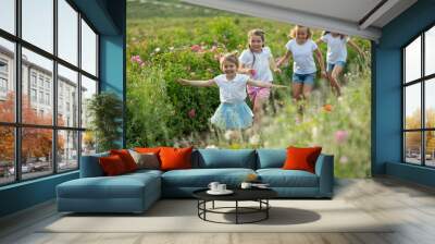 Children play in nature. The girls are having fun running around. Wall mural