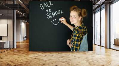 Happy smiling girl. Child at the blackboard. Girl indoor classroom with chalkboard on background. We return to school. High quality photo Wall mural