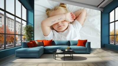 Little girl in bed with white linen. A child at home in the morning wakes up in his room. High quality photo. Wall mural