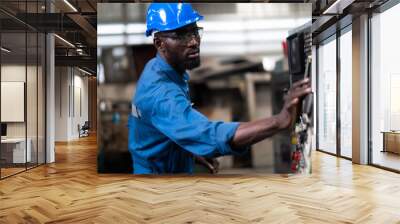 Black Male Engineer Working on machine in Factory. black man engineer checking Quality control the condition of the machine. Service and Maintenance of factory machinery. American African people. Wall mural