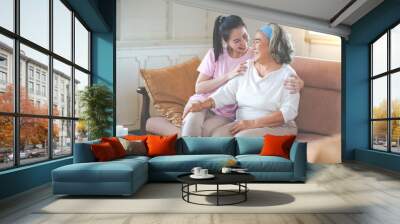 Cute Asian adult daughter embracing her mother with love in living room at home Wall mural