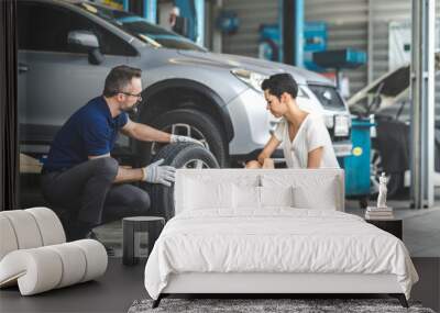 Expertise mechanic man showing the tread of a old tire to a female customer at Car maintenance and auto service garage Wall mural