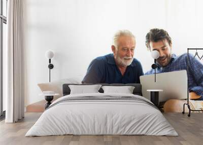 Father and son family time together at home concept. Smiling old father and happy son sitting on sofa using digital laptop computer in living room at home Wall mural