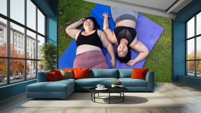 Females couples laying in grass looking up at sky. beautiful young chubby overweight woman in sportswear doing exercise outdoors at park. fitness sport club, body and health care. Activity Wall mural