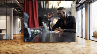 handsome young African American man looking at laptop computer screen. Black businessman working on laptop computer at the club. Wall mural