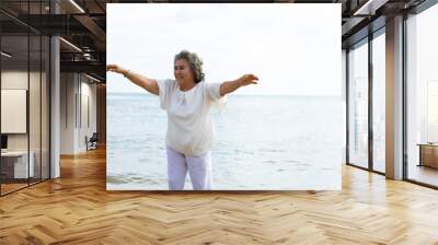 happy elderly woman doing exercise on beach. Wall mural