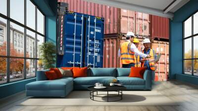 Hispanic man harbor worker talking on the walkie-talkie radio and control loading containers at container warehouse. container yard port of import and export goods Wall mural