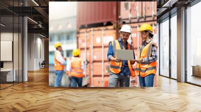 Hispanic Man worker and woman Supervisor checking and control loading Containers box by laptop computer at container yard port of import and export goods. Unity and teamwork concept Wall mural