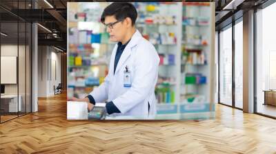 Male working on computer. Pharmacy Drugstore. Portrait Professional Pharmacist handsome asian man at pharma store. Health and wellness center Wall mural