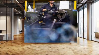 Man Worker at industrial factory wearing uniform and hardhats. Mechanical engineer working at lathe industry factory. Wall mural