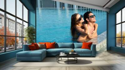 piggyback ride on the back. happy young couple by the pool. couple are relaxing at swimming pool party. Summer vacation holiday trip concept Wall mural