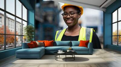 Plus size black female worker wearing safety hard hat helmet inspecting old car parts stock while working in automobile large warehouse Wall mural