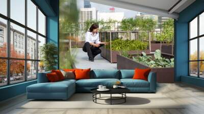 Portrait of female gardener working in Rooftop vegetable garden at the modern building. Agriculture in urban on the rooftop of the building Wall mural