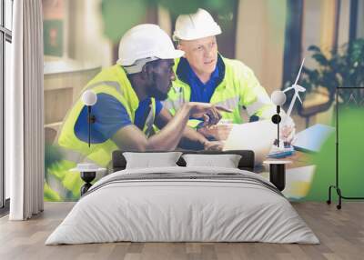 Two engineers African american engineer and caucasian electrician wearing white hard hat working on laptop computer at workplace office. clean and green alternative energy concept. Wall mural