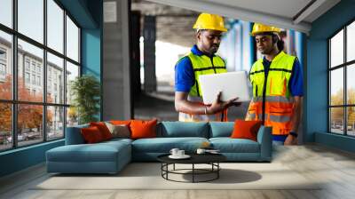 Two men warehouse indian worker wearing safety hardhats helmet working on laptop computer in warehouse of Wholesale Merchandise. shelves, pallets and boxes. Container and warehouse factory Wall mural