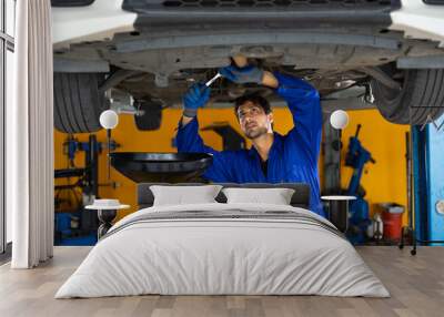 Under car. hispanic latin male mechanic repairs car in garage. Closeup hand. Auto car mechanic checking the oil level of the car engine. Car repair and maintenance Wall mural