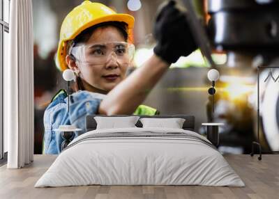 Woman worker wearing safety goggles control lathe machine to drill components. Metal lathe industrial manufacturing factory Wall mural