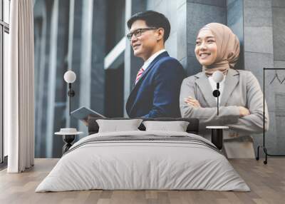 Young business muslim woman and business man colleague massaging on mobile phone in city outdoor. Wall mural