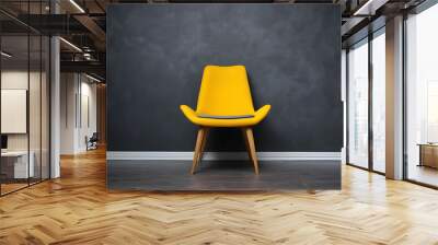 Stylish bright yellow chair against a dark gray wall. Stylish chair on wall background, copy space, fashionable interior Wall mural