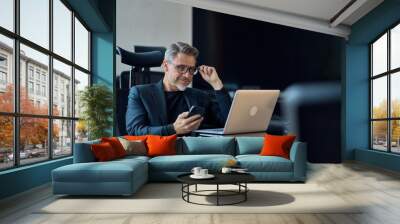 Business portrait - Businessman working with laptop computer sitting in meeting room in modern office. Happy middle aged, mid adult, mature age man smiling. Wall mural