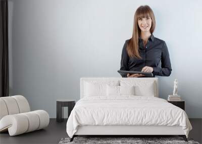 Business portrait of woman - happy young white businesswoman in business casual standing against gray wall using tablet. Copy space for text. Wall mural