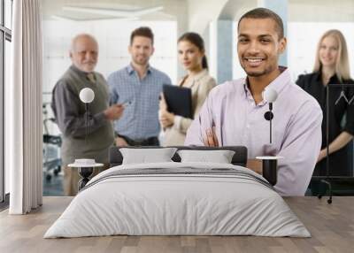 Confident young businessman smiling happy with a team behind. Wall mural