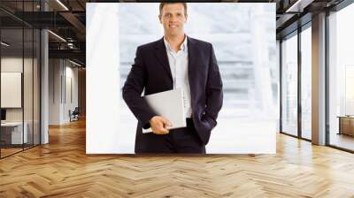 happy businessman holding laptop computer indoor smiling Wall mural