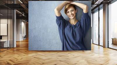 Happy young woman in blue jeans posing at wall Wall mural