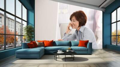 mature businesswoman talking on landline phone Wall mural