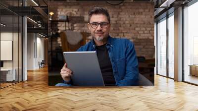 Older man sitting at home using tablet Wall mural