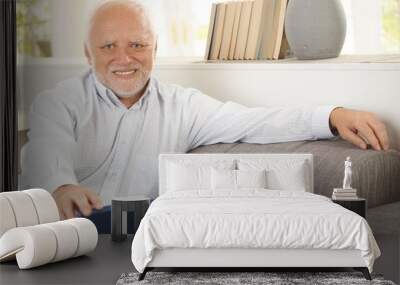 Portrait of elderly man sitting on sofa Wall mural