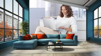 Pretty woman using laptop computer at home Wall mural