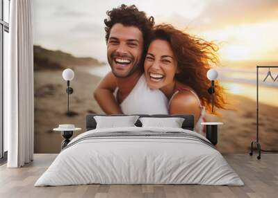 Young couple in their thirties on the beach laughing while riding piggyback at sunset Wall mural