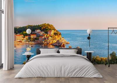 Picturesque summer view of Adriatic sea coast in Budva Riviera. Przno village with buildings on the rock at sunset warm sunlight, Montenegro Wall mural