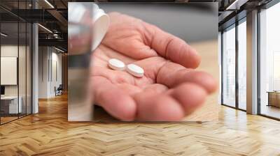 White pills of painkiller or antibiotic for treatment on senior woman hand palm, glass with water, medicines and vitamin supplements concept,close-up view Wall mural