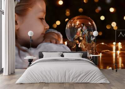 Girl looking at a glass ball with a scene of the birth of Jesus Christ Wall mural