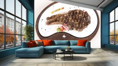 Succulent grilled large t-bone steak garnished with herbs, radish and salt, on a white plate; brown background Wall mural