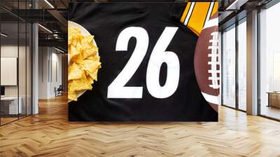 An American football with organic nacho chips and mild salsa on a white black football jersey with the 26 number on horizontal view Wall mural