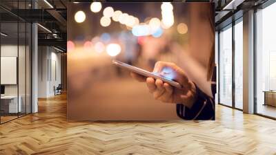 Close up Hand of woman using Mobile smartphone in the street, night light bokeh Background, copy space. Wall mural