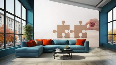 Closeup hand of woman connecting jigsaw puzzle on table wood, Business solutions, success and strategy concept Wall mural