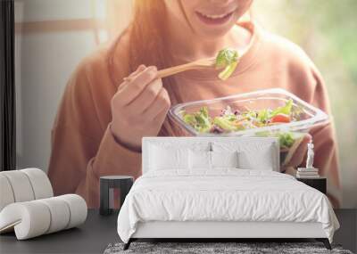 Closeup woman eating healthy food salad, focus on salad and fork Wall mural