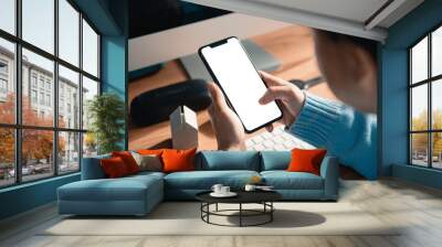 Hand touching mobile smartphone with blank white screen on the desk in the office, copy space. Wall mural