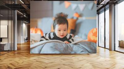 Happy cute asian newborn baby girl dressed in Halloween jack o lantern costume during tummy time having fun and celebrating Halloween at home Wall mural