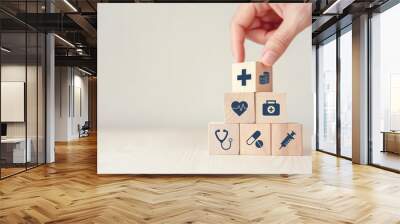 Health Insurance Concept, Hand arranging wood cube stacking with icon healthcare medical on wood background, copy space, financial concept. Wall mural