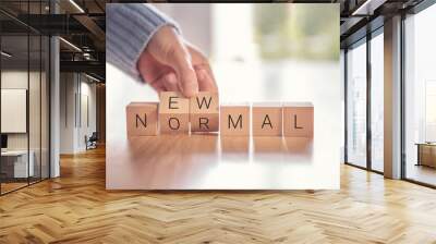 Woman hand arranging wooden cubes with NEW NORMAL word. Adapting to new life or business post-lockdown after coronavirus pandemic. Business with social distancing personal hygiene. Wall mural