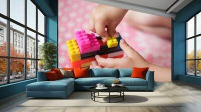 Small hands of the child collects the bright plastic colored Designer. Educational toys and Early learning Wall mural