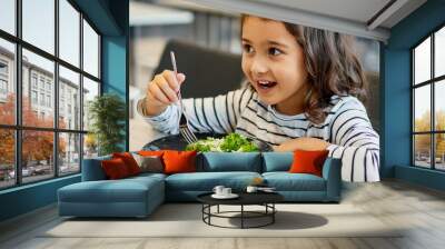 Cute child girl eats healthy food at school cafeteria Wall mural