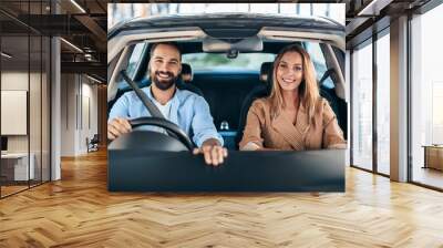 Front portrait of happy man woman couple sitting in modern car enjoying new vehicle Wall mural