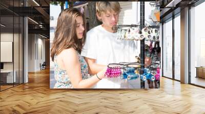 man and woman couple buying fidget spinner from store Tourist souvenir shop selling different colorful spinners in the city street Wall mural